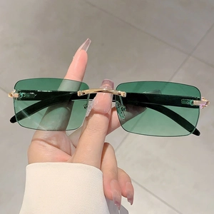 Detailed close-up of rimless sunglasses with emerald green lenses and gold metal accents