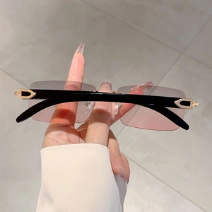 Detail of gradient lenses and golden C-shaped metal hinge on rimless sunglasses