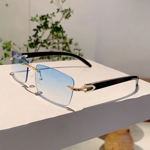 Detail of blue gradient lens and gold C-shaped metal hinge on rimless wood grain sunglasses