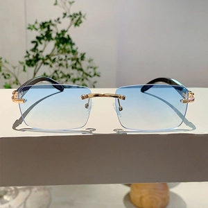 Detail of rimless sunglasses with blue gradient lenses and gold metal nose bridge