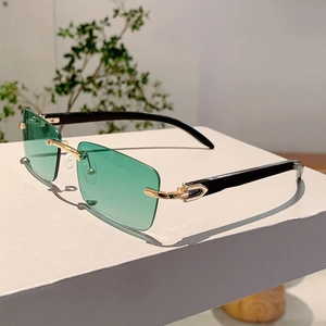 Detail of rimless green rectangular sunglasses with iconic gold C-shaped metal hinge