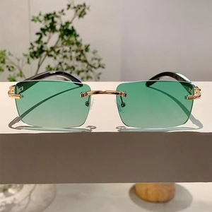 Macro shot of rimless sunglasses with gradient green lenses and gold metal bridge detail