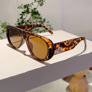 Close-up of vintage tortoiseshell sunglasses with brown lenses on a minimalist stand