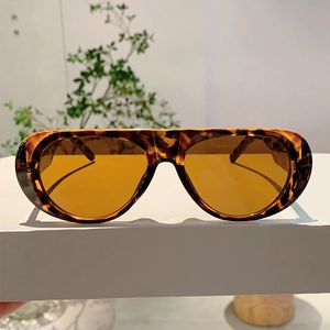 Macro view of oversized retro sunglasses featuring tortoise frames and amber lenses