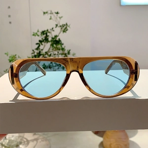 Detail of amber tortoiseshell frame sunglasses with light blue lenses on a white pedestal