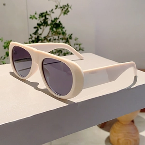 Detail of trendy thick-frame sunglasses in cream beige with dark gray tinted lenses
