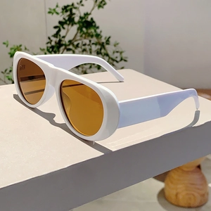 Close-up of white sunglasses with orange lenses on a minimalist geometric display stand