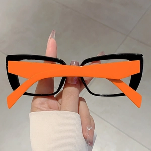 Detail of cat-eye glasses frame with glossy black front and vibrant orange temples