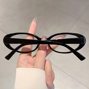Détail de lunettes ovales noires minimalistes avec finition lisse et verres transparents