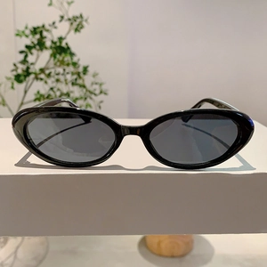 Gros plan de lunettes de soleil œil-de-chat noires brillantes sur un support blanc élégant