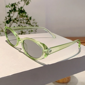Gros plan de petites lunettes de soleil ovales vert translucide sur un socle blanc