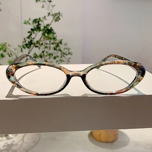 Détail de montures de lunettes ovales à motif marbré coloré sur socle blanc