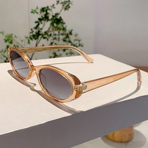 Détail de lunettes de soleil ovales ambre translucide avec verres dégradés gris sur support