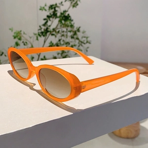 Détail de lunettes de soleil ovales orange avec verres dégradés marron sur support