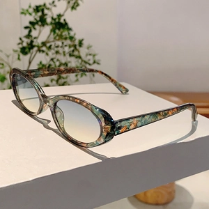 Détail de lunettes de soleil ovales rétro avec texture marbrée colorée et verres bleu dégradé
