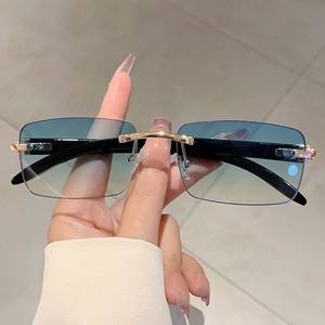 Unisex rimless sunglasses with blue gradient lenses and gold bridge on wood texture temples