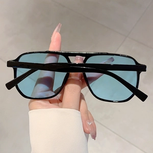 Detail of square black frame sunglasses with blue transparent lenses and double bridge design