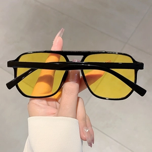 Detail view of retro square black frames with transparent yellow lenses and rice nail rivets