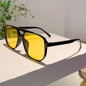 Detail view of vintage aviator sunglasses with yellow lenses and metal rivet accents