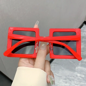 Detail view of bold red square sunglasses featuring wide frames and dark tinted lenses