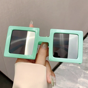 Modern mint green square oversized sunglasses with dark lenses held by hand