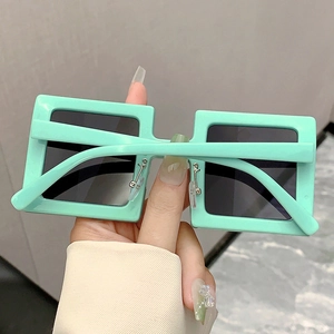 Detail view of bold mint green square sunglasses with dark grey lenses held by a hand
