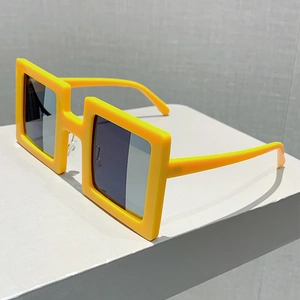 Detailed side view of bold yellow square frames with dark lenses on a pedestal