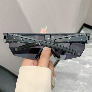Close-up of oversized grey lens sunglasses with artistic black ink splash frame design