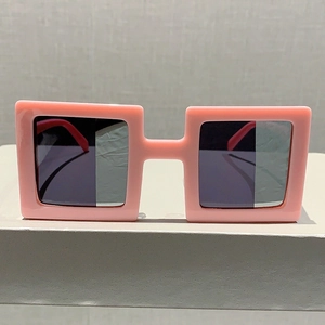 Front view of trendy pink square sunglasses with thick frames and black lenses on white stand