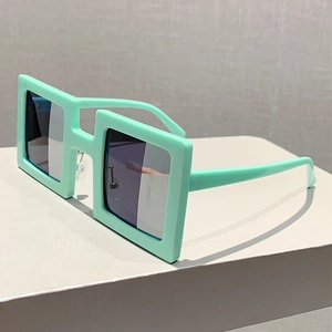 Close-up of mint green square frame sunglasses with wide temples on a geometric stand