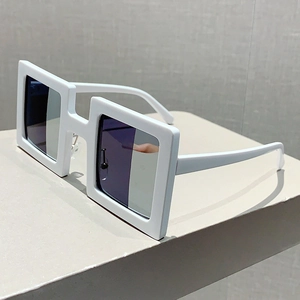 Detail view of bold white square frame sunglasses on minimalist stone display