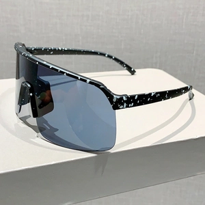 Detail of black sports sunglasses with white splatter pattern and blue oversized lenses