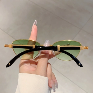 Detail of vintage gold metal frame sunglasses with green lenses and black temples