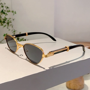 Detailed close-up of oval sunglasses featuring golden metal frames and striped relief texture