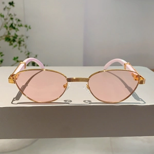 Detail of vintage gold metal sunglasses with light pink lenses and textured hinges