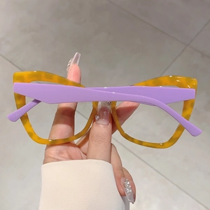 Detail view of bold cat-eye glasses with yellow tortoiseshell frame and purple temples