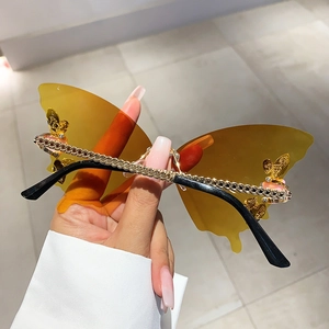 Detail der bernsteinfarbenen schmetterlingsförmigen Sonnenbrille mit goldenen Kettenbügeln