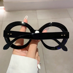 Detailed close-up of thick black round oversized eyeglass frame with gold metal rivets