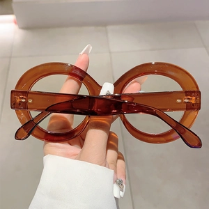 Close-up of hand-held oversized round brown transparent frames with blue light blocking lenses