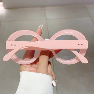 Detail of round pink oversized frame glasses with golden metallic rivets on the hinge
