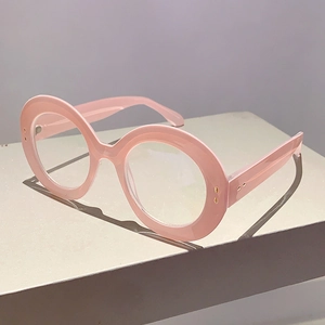 Pink oversized round glasses frames for women on a minimal grey pedestal background