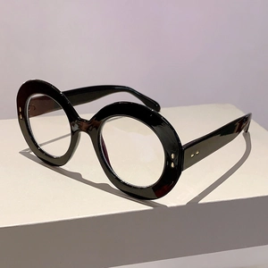 Detailed close-up of black oversized round frames with gold rivets and thick temples