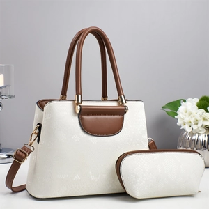 Detail of white textured leather tote bag set with brown handles and gold hardware accents