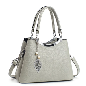 Sac à main élégant en cuir gris avec pendentif feuille et perle sur fond blanc pur