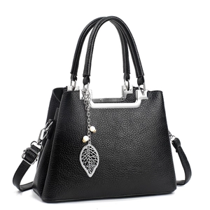 Detail of black pebbled leather handbag with silver hardware and leaf pearl charm