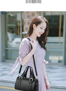 Lifestyle shot of black lychee grain leather handbag with silver rings on floral dress