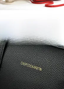 Close-up of premium black lychee pattern leather and elegant gold embossed brand logo