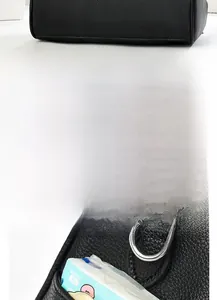 Detail of black litchi grain leather bag showing smooth bottom and side pocket with D-ring