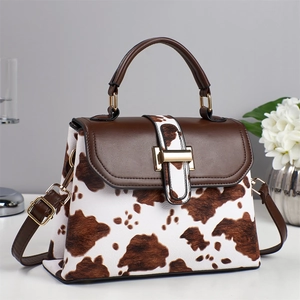 Chic cow print handbag with brown leather flap and gold metal buckle for women