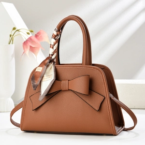 Detailed shot of brown lychee leather handbag with decorative bow and silk scarf handle